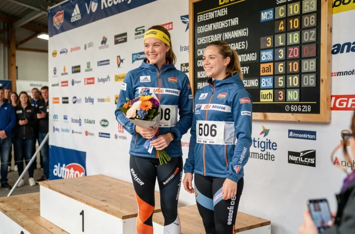 Podium de compétition de biathlon féminin avec tableau des scores et classement des points en arrière-plan